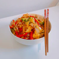 a bowl of asian food with chopsticks