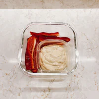 hummus and peppers in a glass container