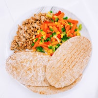 a plate with a bowl of vegetables and pita bread