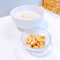 a bowl of cereal with cashew nuts next to it