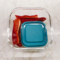 red peppers in a container with a blue lid