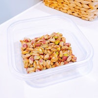 pistachios in a plastic container next to a basket