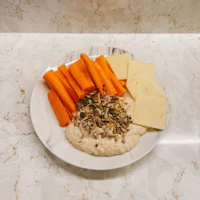 hummus with carrots and cheese on a white plate