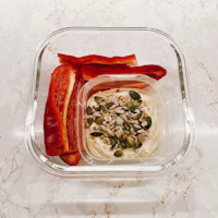 hummus with peppers and seeds in a clear container
