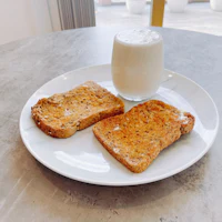 a plate with two slices of toast and a glass of milk