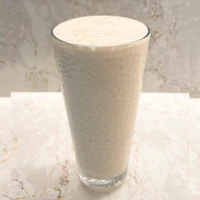 a glass of milk sitting on top of a marble counter