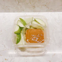 a plastic container with apples and peanut butter