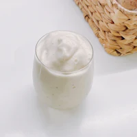 a glass filled with a white smoothie on a marble counter